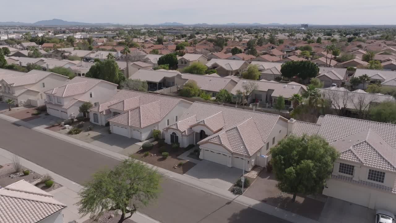 barrio suburbano con filas de casas y árboles bajo un cielo despejado, vista aérea