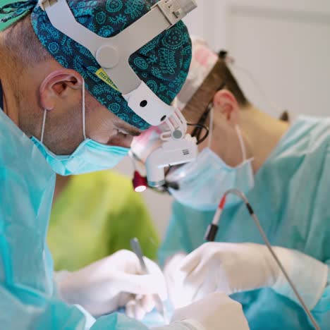 professional doctors during surgery. male specialists in medical uniform and surgical flashlights on head perform an operation to a patient.