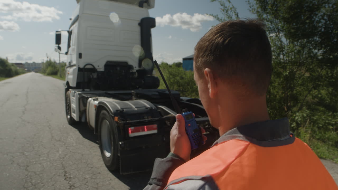 Truck Driver Using Walkie Talkie Near Semi-Truck