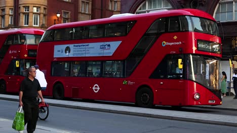 pedestrians and cyclist near iconic red bus