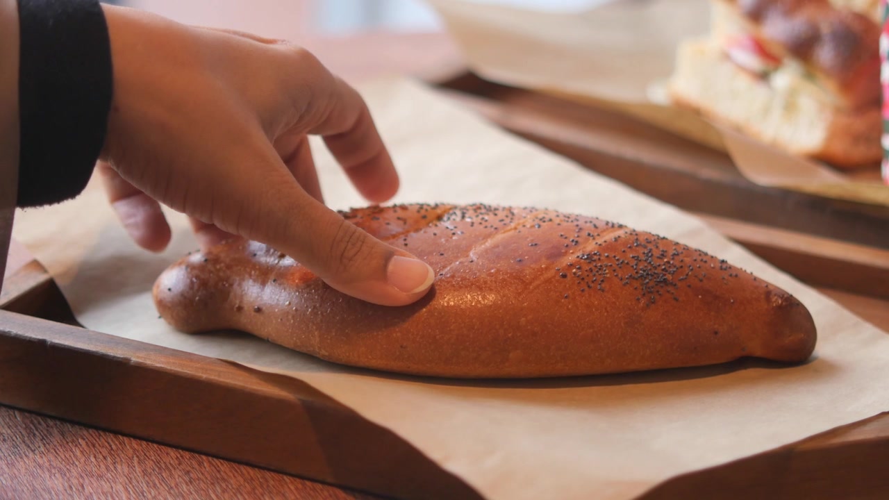 Mano che Prende una Pagnotta di Pane ai Semi di Papavero Appena Sfornata