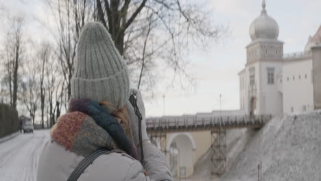 frau, die ein foto von einem schloss im winter macht