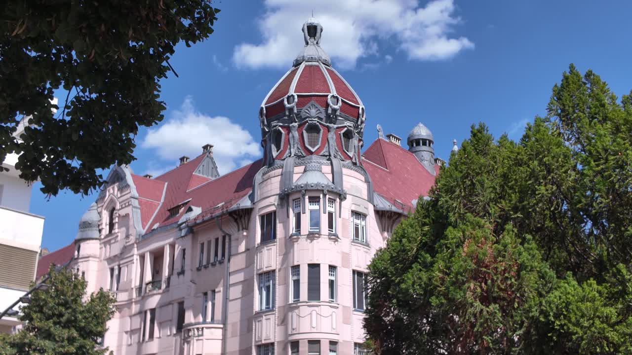 Scenic view of Szeged’s pink historic building with an overcast sky, emphasizing classic European architecture and soft lighting