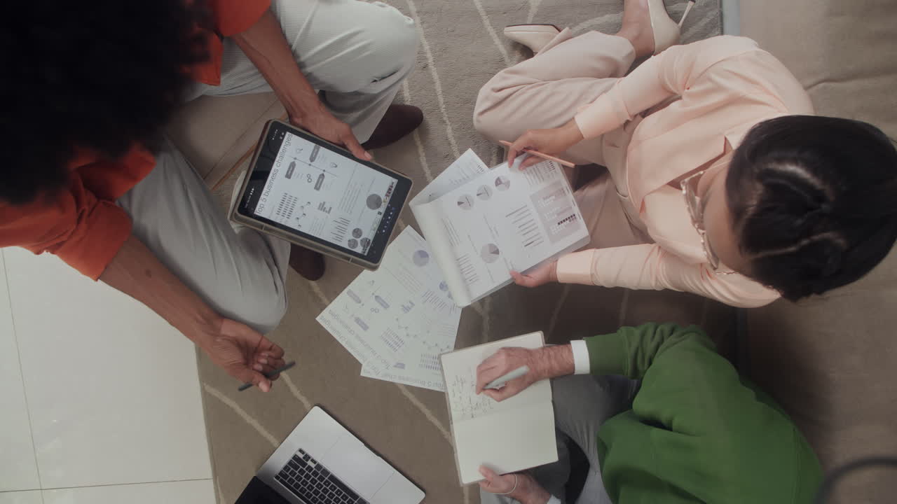 Businesspeople Doing Report Using Tablet and Documents on Floor