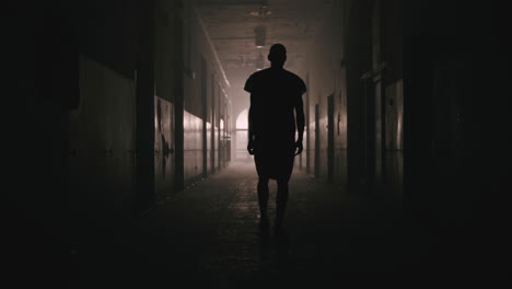 a bald man walks on the empty hospital corridor at night