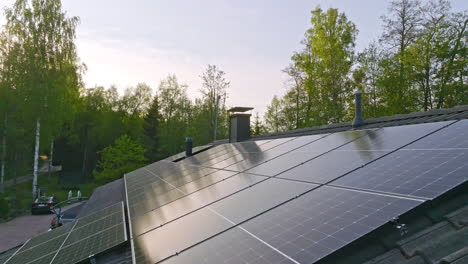 aerial: roof full of solar panels on a private house in the forest, summer sunset