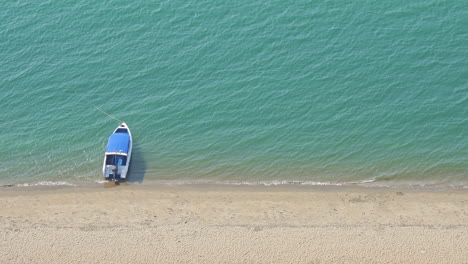 small tourist boat floating in the sea near the white sand beach top view