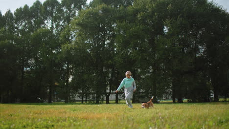 wide view of trainer running with dog in lush green natural park during bright summer day, surrounded by tall trees, open grassy field, relaxed joyful outdoor atmosphere perfect for pet exercise