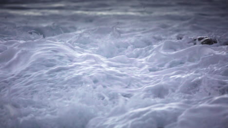 water level view of waves crashing and rolling into a rocky shore in slow motion