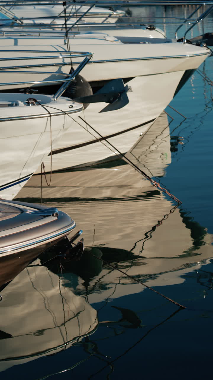 Riflessi distorti di yacht, corde e ancore sulla superficie lucida di un porticciolo. Verticale
