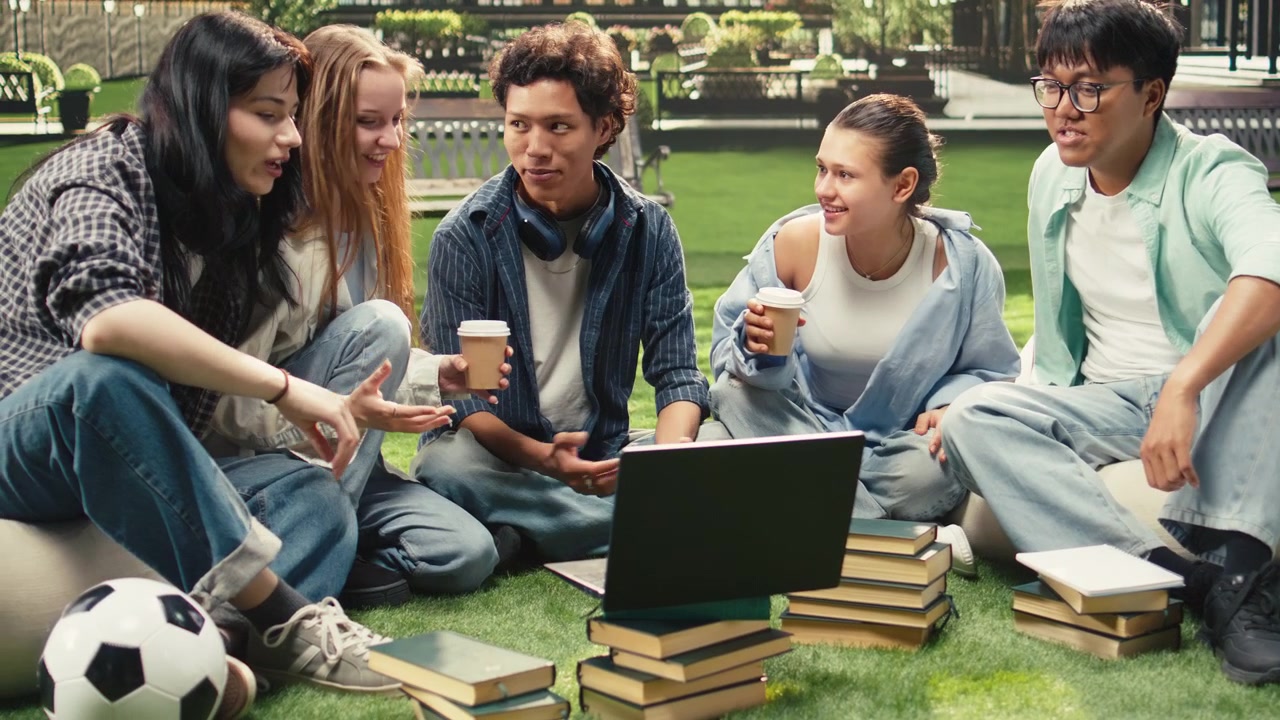 Diverse peers gathering on campus grass for group study session
