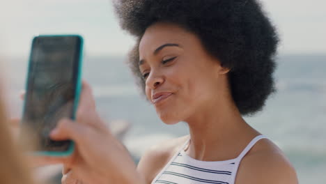 Schöne-Frau-Mit-Afro,-Die-Eis-Am-Strand-Isst-Und-Für-Einen-Freund-Posiert,-Der-Mit-Dem-Smartphone-Ein-Foto-Macht.-Freundinnen-Teilen-Lustigen-Sommertag-In-Den-Sozialen-Medien-4K