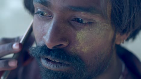indian man close-up of face smeared with bright holi colors