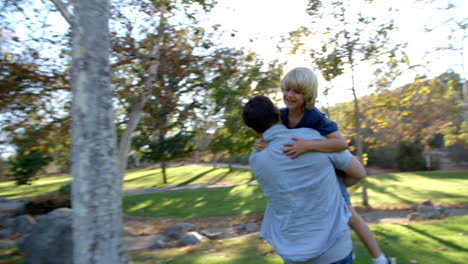 father carries son as they have fun in park together