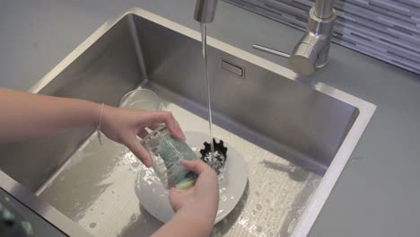 washing dishes with a sponge in a kitchen sink