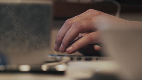 mano trabajando en una laptop en una cafetería, primer plano borroso