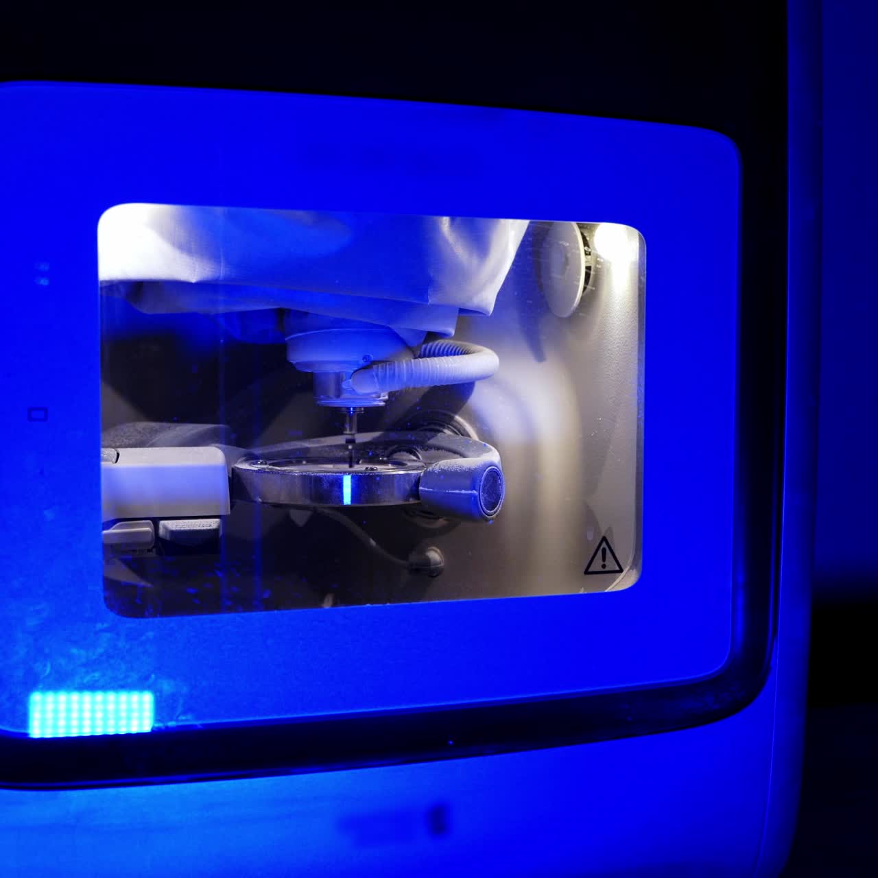 Work of dental device. Advanced milling machine in laboratory. Dental machine carving out shape of human teeth. Modern medical technologies. Blue light