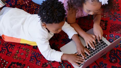 High-angle-view-of-cute-black-siblings-using-laptop-in-living-room-at-comfortable-home-4k