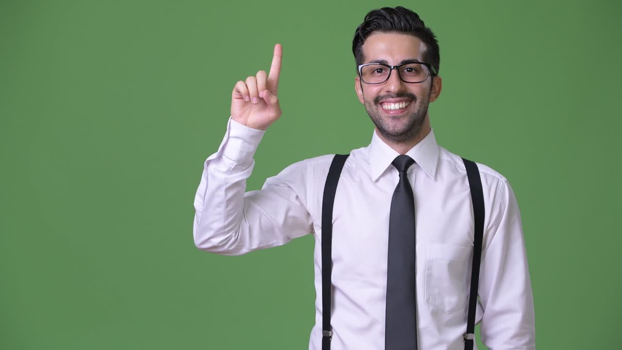 joven empresario persa barbudo y guapo contra un fondo verde