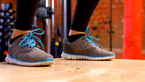 mujer caucásica decidida haciendo sentadillas de salto en el estudio de fitness 4k