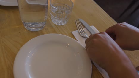 person arranging cutlery on a table