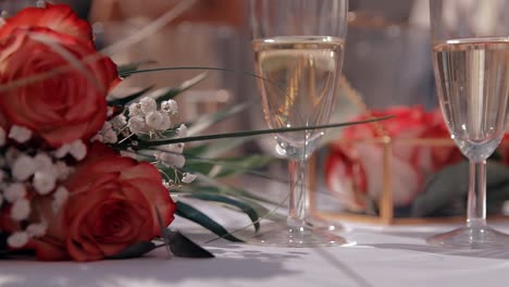 wedding bouquet with two glasses of champagne on a table with a white tablecloth prepared for the wedding couple