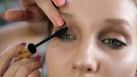 Close-up-of-a-make-up-process,-model's-eyes.-Artist-putting-on-black-mascara.-Front-view