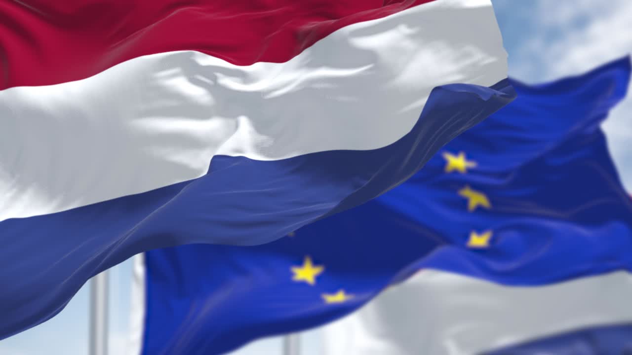바람에 흔들리는 네덜란드 국기와 배경에 흐릿한 유럽 연합 국기