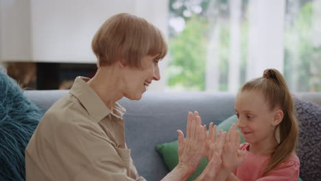 Cheerful-girl-clapping-hands-with-senior-woman-indoors