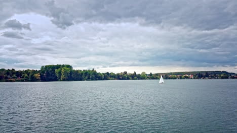 sailboat in a german lake with trees in the background and an impressive sky, 4k