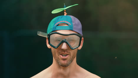 pink-water-balloon-exploding-on-man-in-extreme-slow-motion,-male-wearing-googles-and-colorful-hat-braces-for-impact-and-gets-hit-in-the-face-water-splashing-everywhere-in-4k-800fps