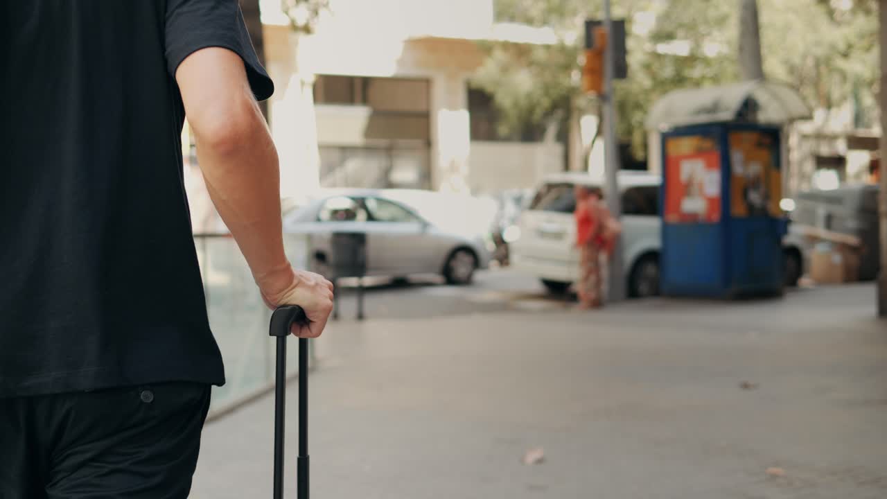 Turistmand med kuffertbagage i Spanien. En rejsende med bagage og jakkesæt på en forretningsgade på vej til et hotel, forretningskontor, lufthavnsterminal, mens han nyder den livlige atmosfære.