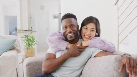 Portrait-of-happy-diverse-couple-embracing-in-living-room
