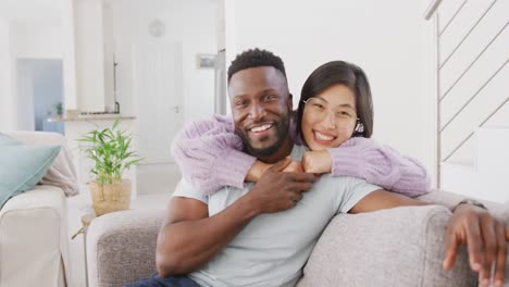 portrait of happy diverse couple embracing in living room