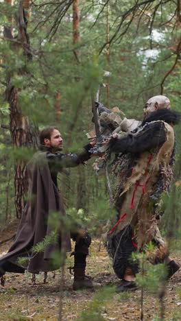 valiente caballero lucha con un gran orco feo en el bosque de abeto glade cámara lenta. batalla de guerrero medieval y monstruo. juego tolkienista y rendimiento