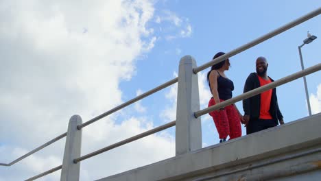 happy couple interacting with each other while walking near railing 4k