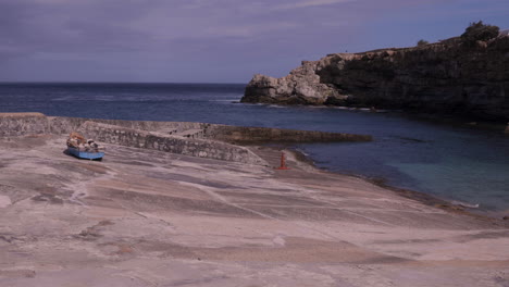 Panning-shot-of-historic-harbour-in-Hermanus,-South-Africa-with-cliffs-in-the-background