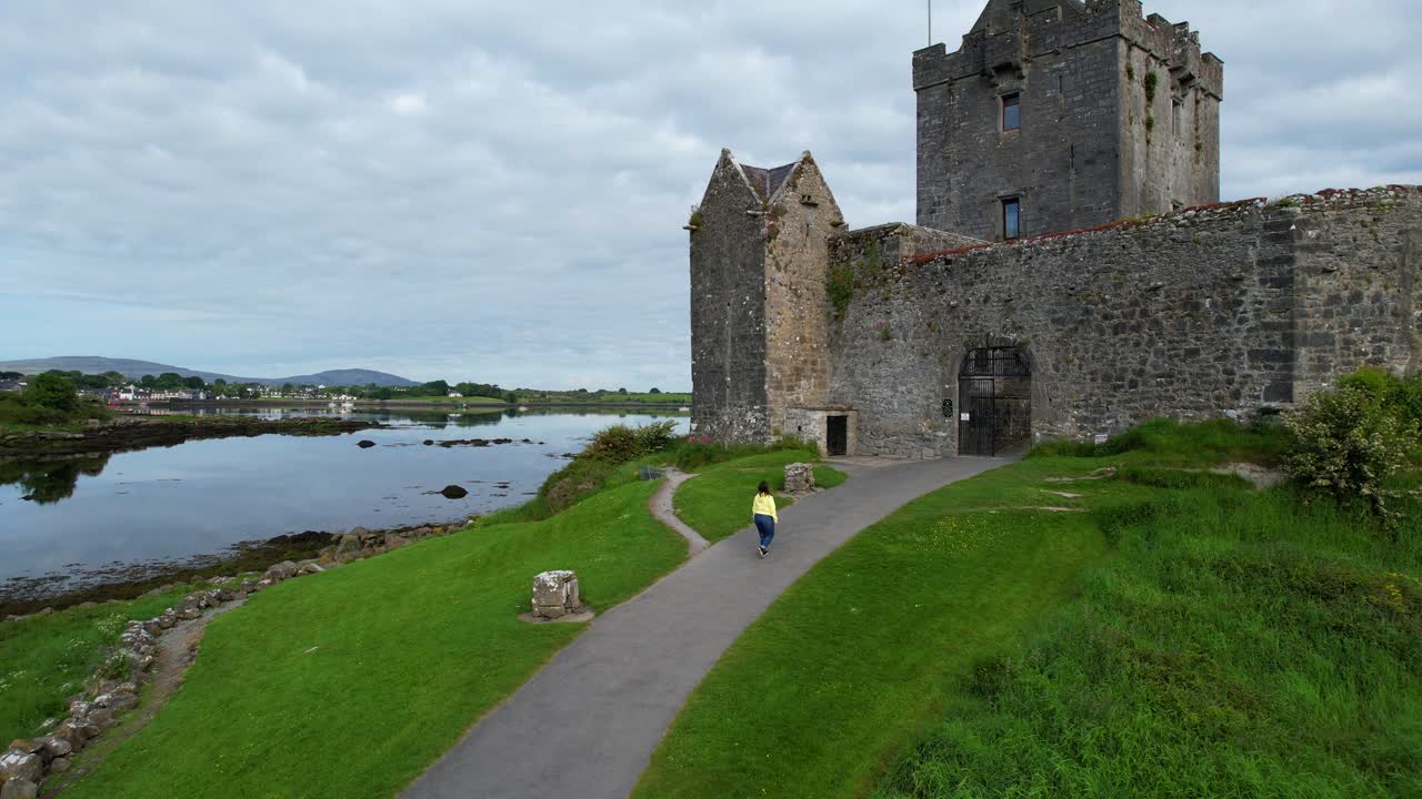 낮은 공중 추적 여자 dunguaire 성 입구로 걸어