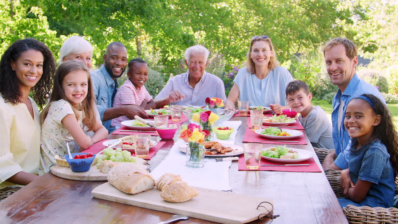 Friends and family having lunch in garden, looking to camera