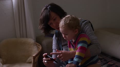 Caucasian-woman-with-baby-looking-smartphone-at-home