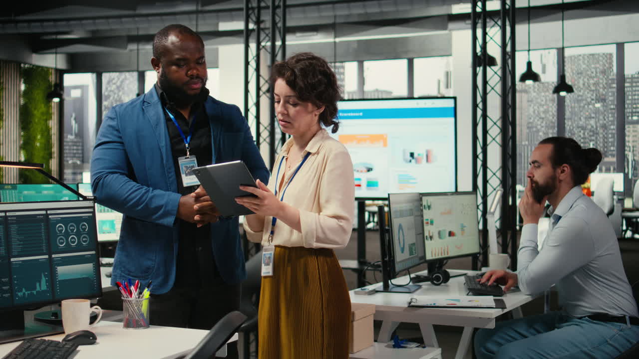 Vertical Video Two employees reviewing data insights on tablet in professional workspace