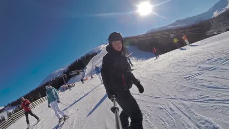 front selfie stick view of a snowboarder going down in slow motion and people around