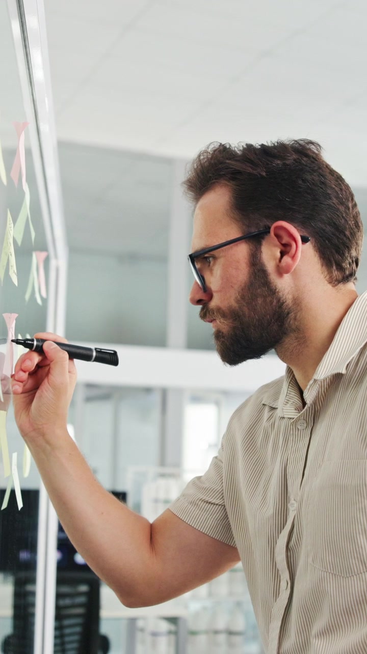 Uomo professionista che scrive su una parete di vetro in un ufficio moderno