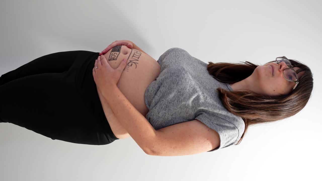 молодая беременная женщина с любовью касается ее круглого живота. вертикальный вид