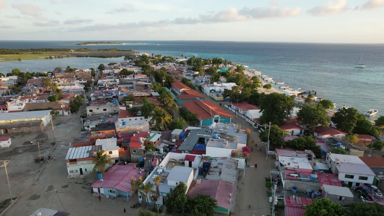 Gran roque village at sunset, calm ocean, colorful rooftops, serene mood, aerial view