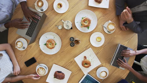 overhead shot of businesspeople meeting around coffee shop table