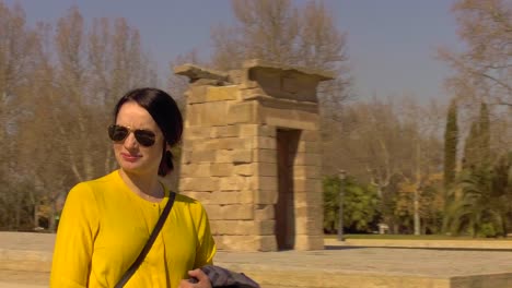 Young-female-tourist-walking-past-the-Egyptian-monument,-Temple-of-Debod,-in-Madrid