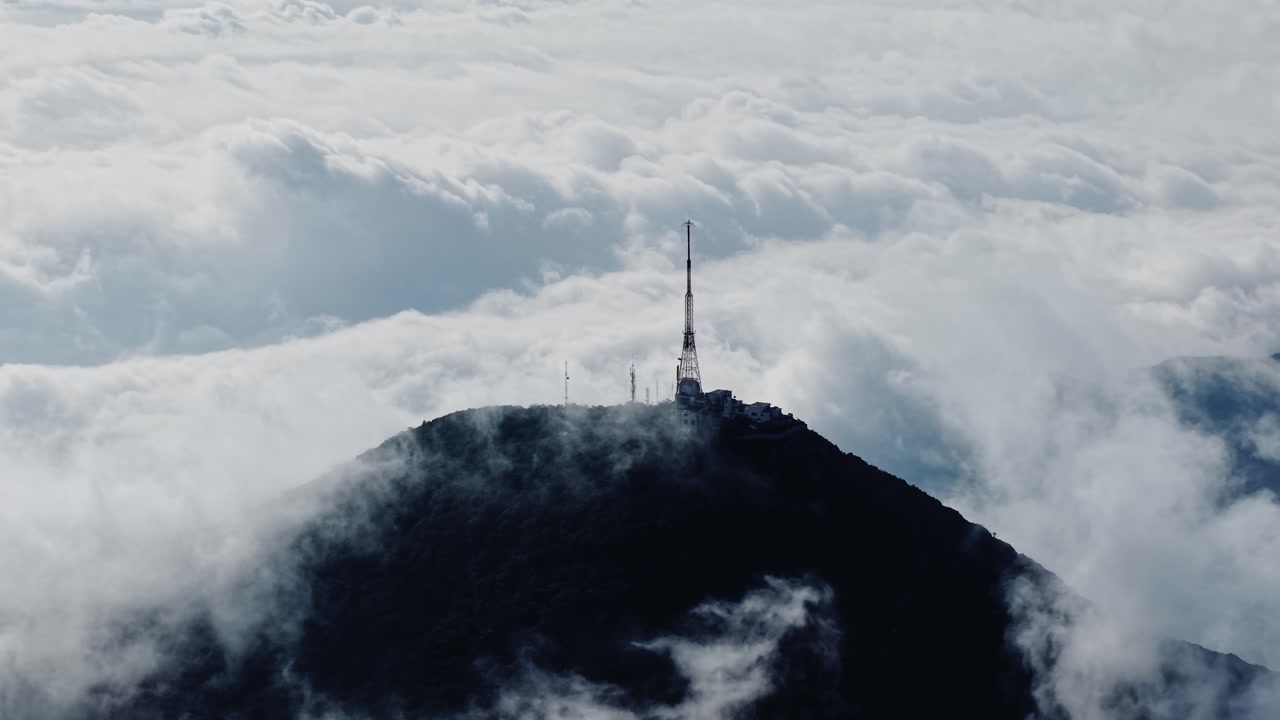 Cloud-covered mountain peak with tower, peaceful and serene atmosphere