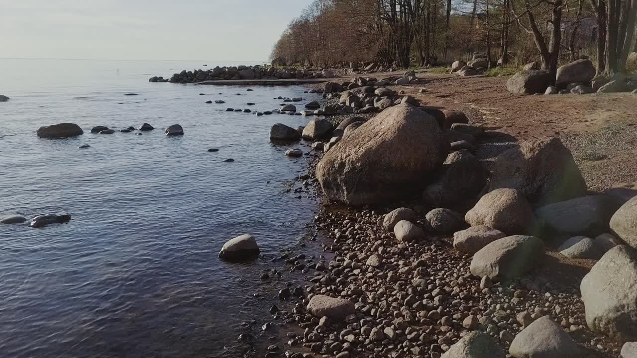 Felsstrand mit vielen Findlingen und blauem Meer, nordische Natur.