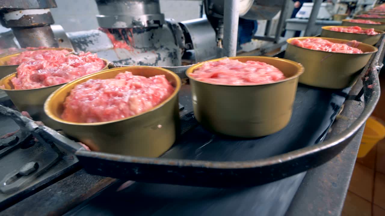 cerca de latas de hojalata llenas de carne moviéndose alrededor de la cinta transportadora